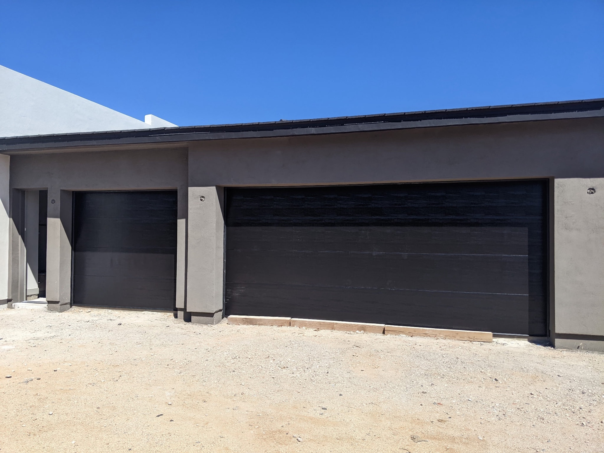 Sleek black modern doors on contemporary stucco home